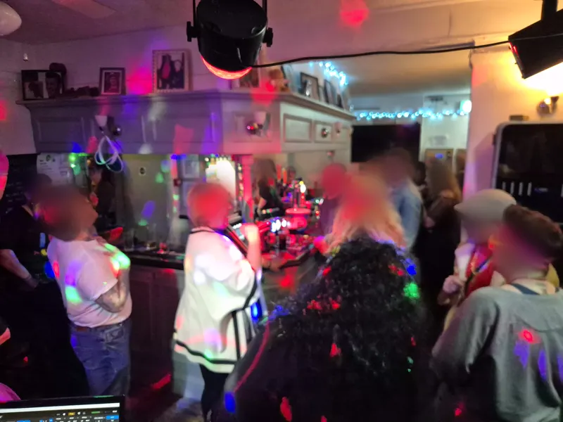 Crowd dancing by the bar with party lights across the ceiling